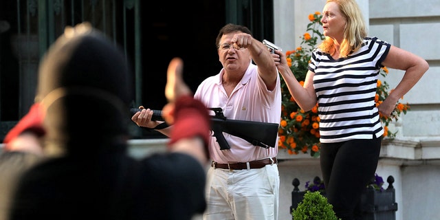 Armed homeowners Mark T. and Patricia N. McCloskey stand in front their house as they confront protesters marching to St. Louis Mayor Lyda Krewson's house on June 28, 2020.  