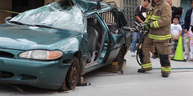 FILE - A firefighter uses the 'jaws of life' tool to remove the doors of a vehicle.