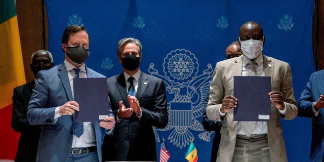 U.S. Secretary of State Antony Blinken (background L) applauds as ABD Group CEO John Nevergole (L) and Ageroute Director General Ibrahima Ndiaye (R) sign an agreement during a commercial diplomatic event with U.S. companies and the government of Senegal at the Radisson Blu Hotel in Dakar, on November 20, 2021.