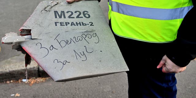 A police expert holds a fragment of a drone with a handwritten inscription reading "For Belgorod. For Luch" after a drone attack in Kyiv on Oct. 17, 2022, amid the Russian invasion of Ukraine. 