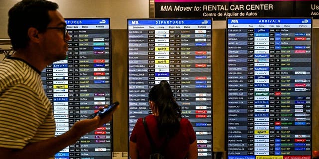 Travelers look at flight schedules at Miami International Airport during a winter storm ahead of the Christmas holiday in Miami, Florida, on December 23, 2022. - Nearly a million-and-a-half US power customers were in the dark Friday as a severe winter storm walloped the country, causing highway closures and thousands of flight cancellations days before Christmas. Heavy snow, howling winds, and air so frigid it instantly turned boiling water into ice took hold of much of the nation, including normally temperate southern states. (Photo by CHANDAN KHANNA / AFP) 