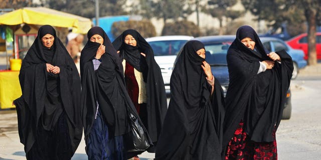 TOPSHOT - Afghan burqa-clad women walk through a street in Kabul on December 28, 2022. 