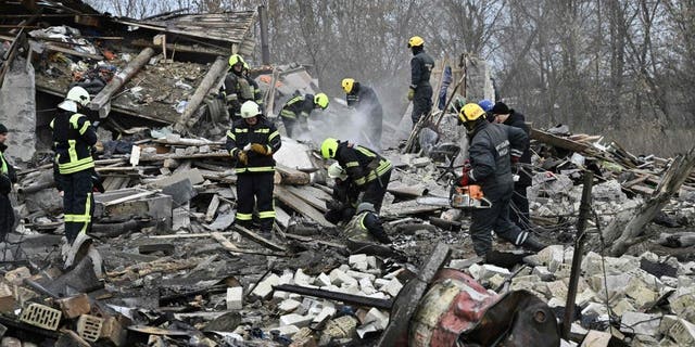 TOPSHOT - Rescuers clear debris of homes destroyed by a missile attack in the outskirts of Kyiv, on December 29, 2022, following a Russian missile strike on Ukraine. 