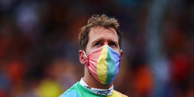 Sebastian Vettel of Germany and wears a rainbow-color T-shirt and face mask as he looks on from the grid before the F1 Grand Prix of Hungary on Aug. 1, 2021, in Budapest, Hungary.