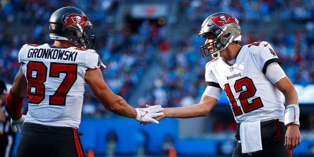 Tom Brady, #12, and Rob Gronkowski, #87 of the Tampa Bay Buccaneers, react after a touchdown during the third quarter in the game against the Carolina Panthers at Bank of America Stadium on Dec. 26, 2021 in Charlotte, North Carolina. 