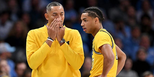 Michigan Wolverines head coach Juwan Howard talks with Jett Howard, #13, during the second half of their game against the North Carolina Tar Heels at Spectrum Center on Dec. 21, 2022 in Charlotte, North Carolina. The Tar Heels won 80-76. 