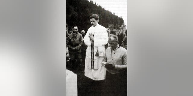 A photo taken during the summer 1952 near Ruhpolding, shows German priest Joseph Ratzinger (C) praying during an open-air mass. 