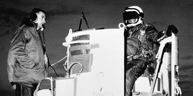 FILE - In this photo provided by the U.S. Air Force, Capt. Joseph Kittinger Jr., aerospace laboratory test director, sits in the open balloon gondola after his first parachute test jump for Project Excelsior at the Air Force Missile Development Center, N.M., Nov. 16, 1959. The gondola carried him at an altitude of 76,400 feet for his record free fall jump of more than 12 miles. At left is David Willard, who designed and developed special equipment for the gondola.