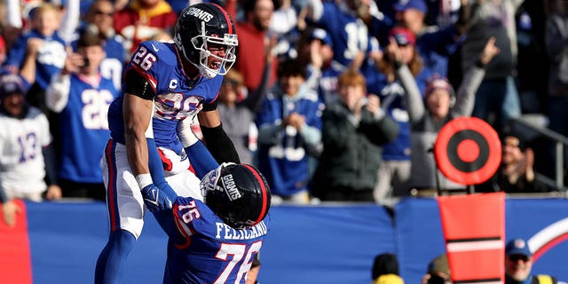 Saquon Barkley #26 celebrates with Jon Feliciano of the New York Giants after scoring a touchdown in the second quarter against the Washington Commanders at MetLife Stadium, Dec. 4, 2022, in East Rutherford, New Jersey.