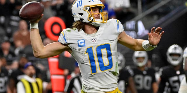 Los Angeles Chargers quarterback Justin Herbert, #10, passes under pressure from Las Vegas Raiders defensive end Maxx Crosby, #98, during the second half of an NFL football game, Sunday, Dec. 4, 2022, in Las Vegas.