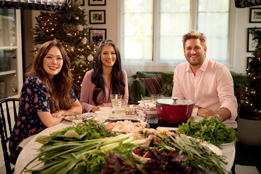 Photo of Lindsay, Kelly Hu and Curtis. They're seated around a table that has lots of vegetables on it. Lindsay and Curtis are flanking Kelly.