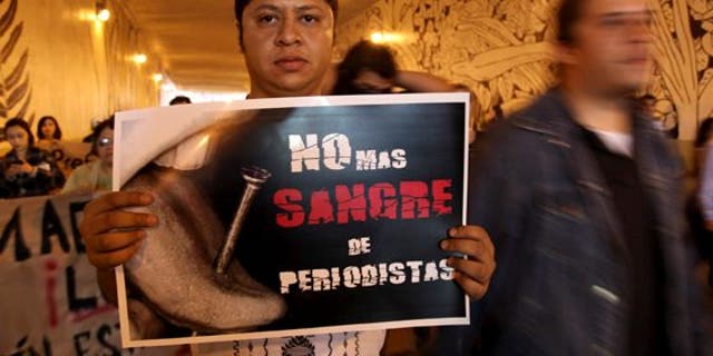 A man carrying a sign saying "No more blood of journalists" during a protest to demand justice for a slain journalist.