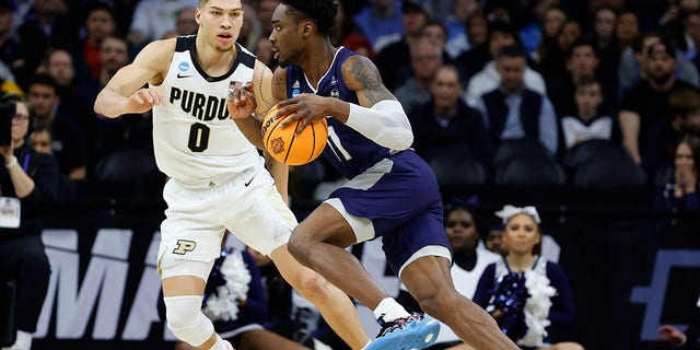 KC Ndefo of the St. Peter's Peacocks dribbles the ball as Mason Gillis of the Purdue Boilermakers defends at Wells Fargo Center on March 25, 2022, in Philadelphia.