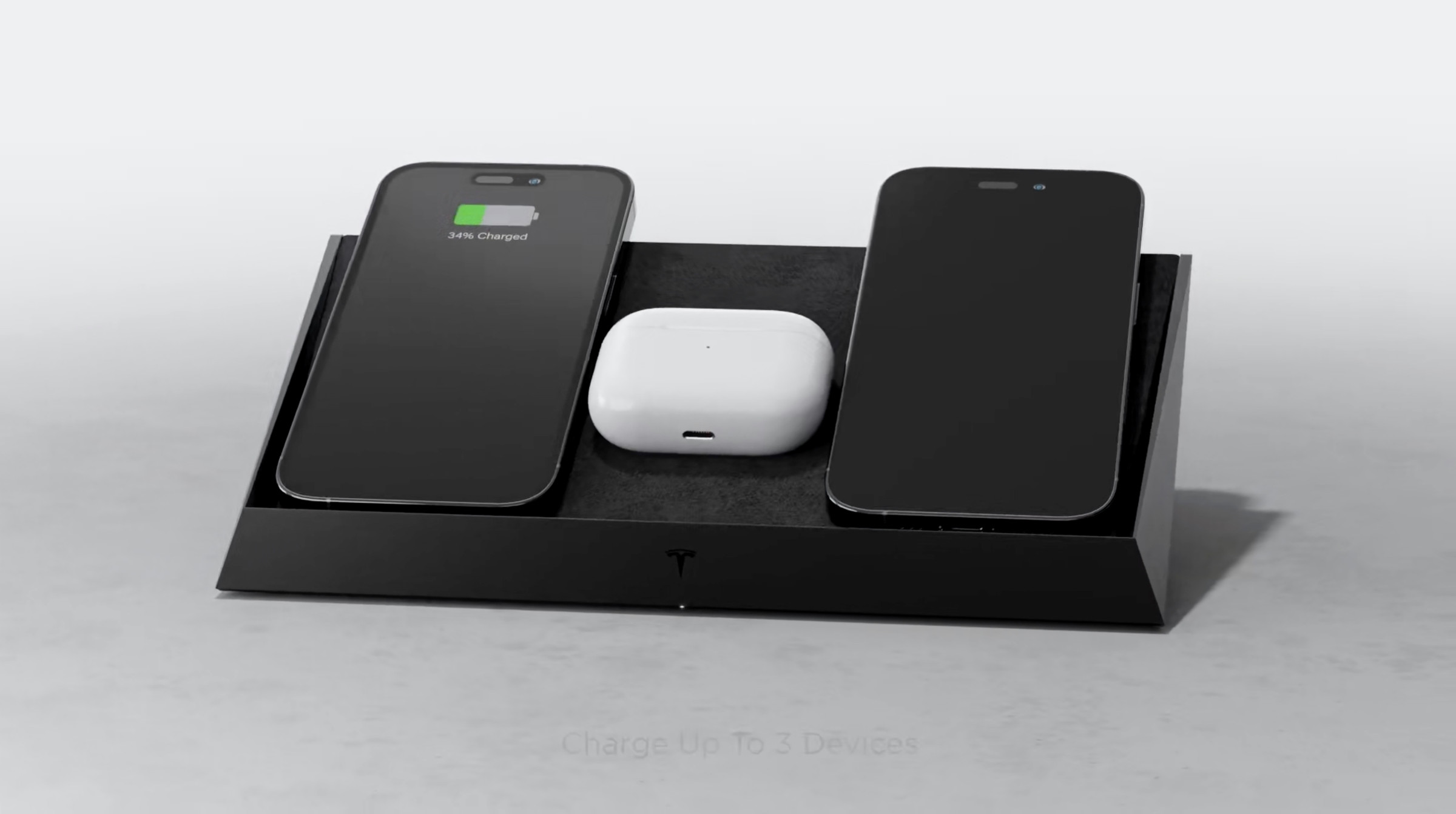 Image of the Tesla charging pad with two iPhones and a set of AirPods on it.