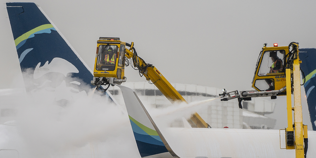 Workers deice an Alaska Airlines plane during a snow storm at Seattle-Tacoma International Airport in Seattle on Dec. 20, 2022.