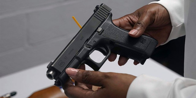 A handgun from a collection of illegal guns is reviewed during a gun buyback event in Brooklyn, N.Y., May 22, 2021.