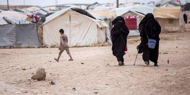 Women walk in the al-Hol camp that houses some 60,000 refugees, including families and supporters of the Islamic State group, many of them foreign nationals, in Hasakeh province, Syria, May 1, 2021. 