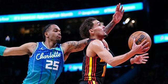 Atlanta Hawks guard Trae Young, right, drives to the basket past Charlotte Hornets forward P.J. Washington during the first half, April 13, 2022, in Atlanta.