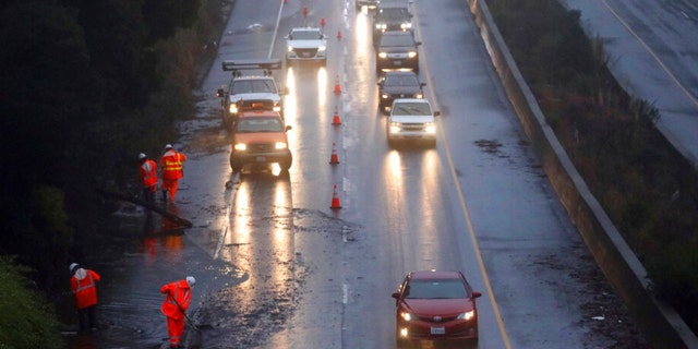 A Caltrans crew works to clear a flooded portion of northbound Highway 13 on Tuesday, Dec. 27, 2022, in Oakland, California.