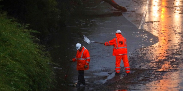 A Caltrans crew works to clear a flooded portion of northbound Highway 13 on Tuesday, Dec. 27, 2022, in Oakland, California.