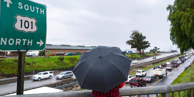 A woman watches cars stopped in the northbound lanes of Highway 101 after flooding closed the highway near Chualar, California, Tuesday, Dec. 27, 2022.