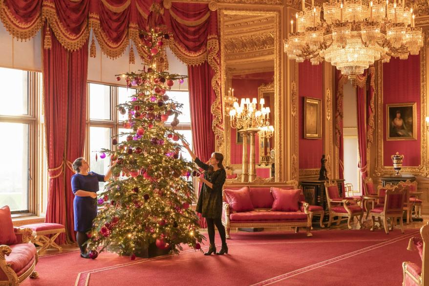 Royal Collection Trust staff put the finishing touches to the Nordmann Fir Christmas tree in the Crimson Drawing Room, one of the ornate Semi-State Rooms.