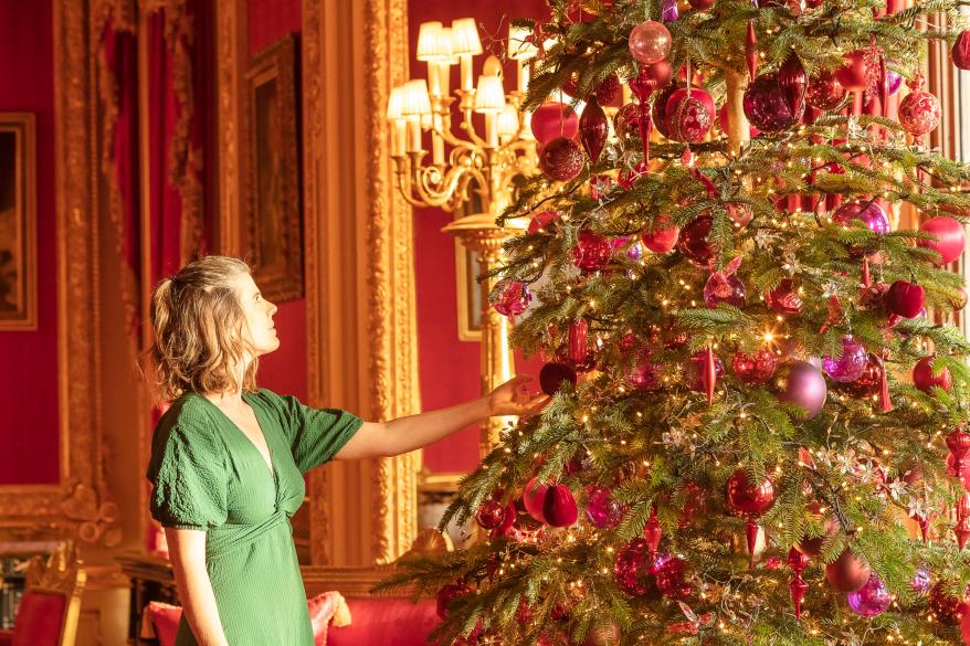 Royal Collection Trust staff put the finishing touches to the Nordmann Fir Christmas tree in the Crimson Drawing Room, one of the ornate Semi-State Rooms.