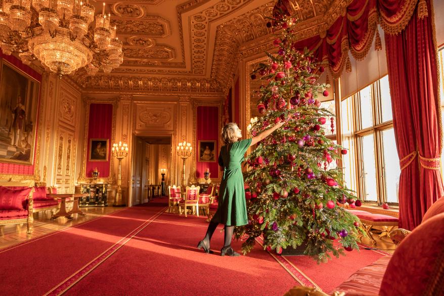 Royal Collection Trust staff put the finishing touches to the Nordmann Fir Christmas tree in the Crimson Drawing Room, one of the ornate Semi-State Rooms.