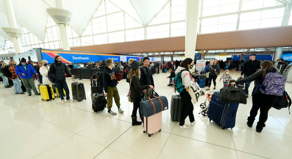 Travelers queue up to check in at the Southwest Airlines counter in Denver International Airport after a winter storm swept over the country packing snow combined with Arctic cold, which created chaos for people trying to reach their destinations before the Christmas holiday, Friday, Dec. 23