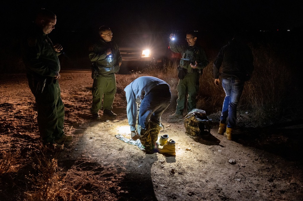 A Mexican immigrant captured by U.S. Border Patrol agents removes camouflage while being taken into custody near the U.S.-Mexico border on November 03, 2022 near Douglas, Arizona.