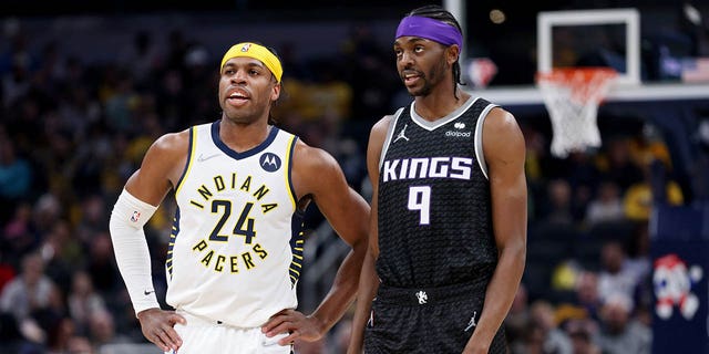 Buddy Hield (24) of the Indiana Pacers and Justin Holiday (9) of the Sacramento Kings meet in the first quarter at Gainbridge Fieldhouse March 23, 2022, in Indianapolis.