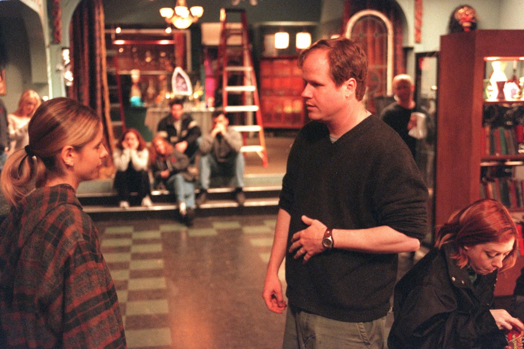 Joss Whedon,(right), creator, writer and director of Buffy the Vampire Slayer talks to Sarah Michelle Gellar, with cast in background.