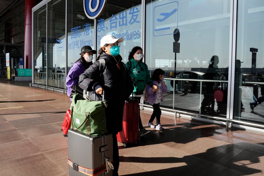 Passengers wearing masks walk through the Capital airport terminal in Beijing on Dec. 13, 2022. 