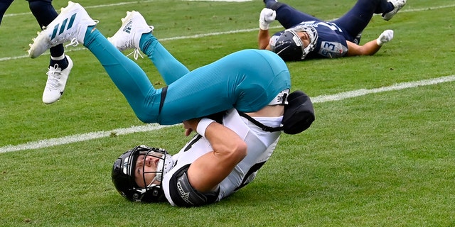 Jacksonville Jaguars quarterback Trevor Lawrence, left, scores past Tennessee Titans linebacker Dylan Cole (53) during the second half of a game Sunday, Dec. 11, 2022, in Nashville, Tenn. 