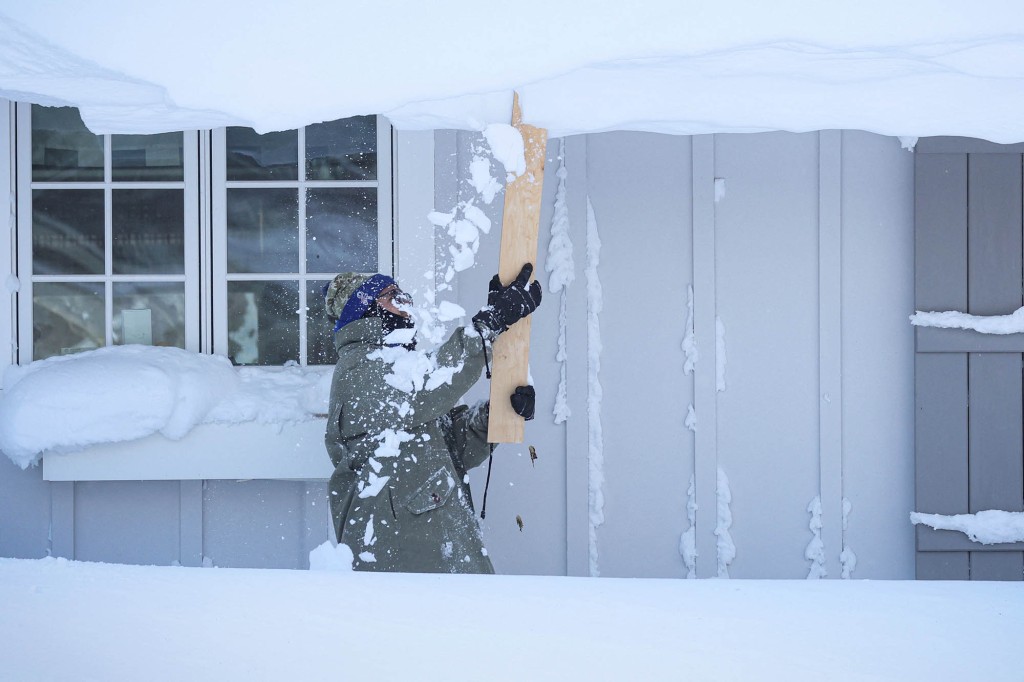 A man clears snow from his roof in Amherst, New York.