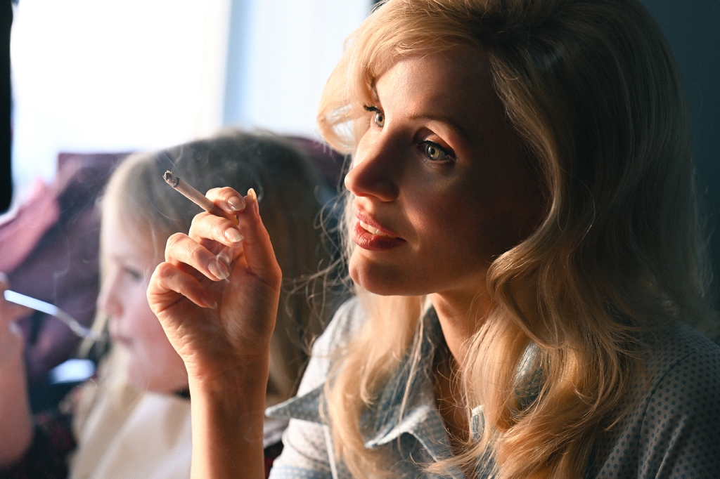 Jessica Chastain as Tammy Wynette in "George & Tammy" on Paramount+. She's got long hair and is holding a cigarette in her hand. She's looking off-camera with a slight smile on her face.