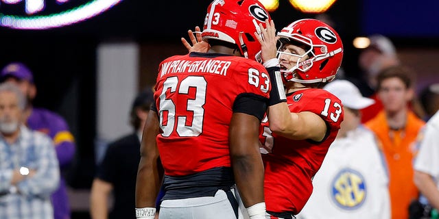 Stetson Bennett (13) and Sedrick Van Pran (63) of the Georgia Bulldogs celebrate a touchdown against the LSU Tigers during the first quarter of the SEC championship game at Mercedes-Benz Stadium Dec. 3, 2022, in Atlanta. 