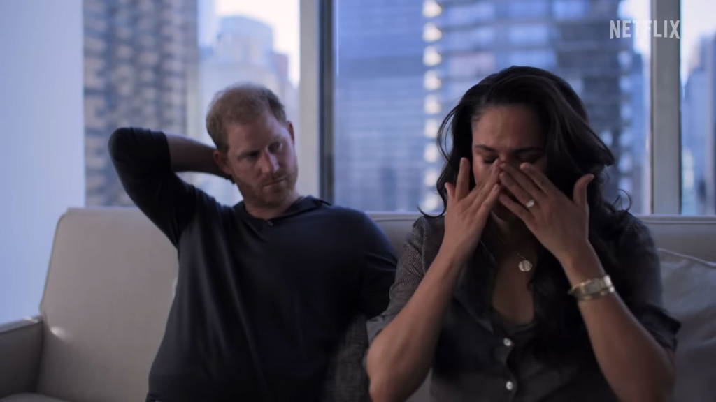 Photo of Prince Harry and Meghan on a couch, Meghan is crying.