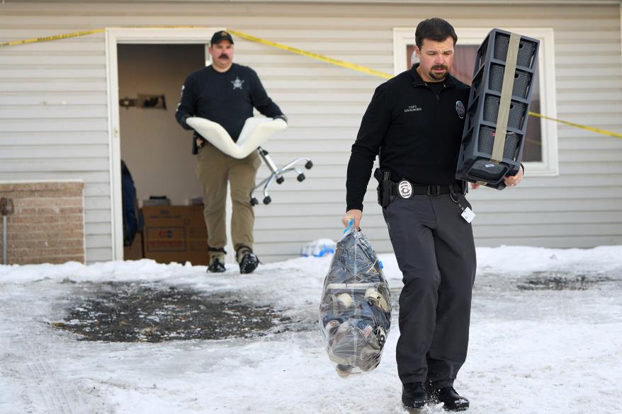 Police carry shoes of the victims outside of their Moscow, Idaho, home.