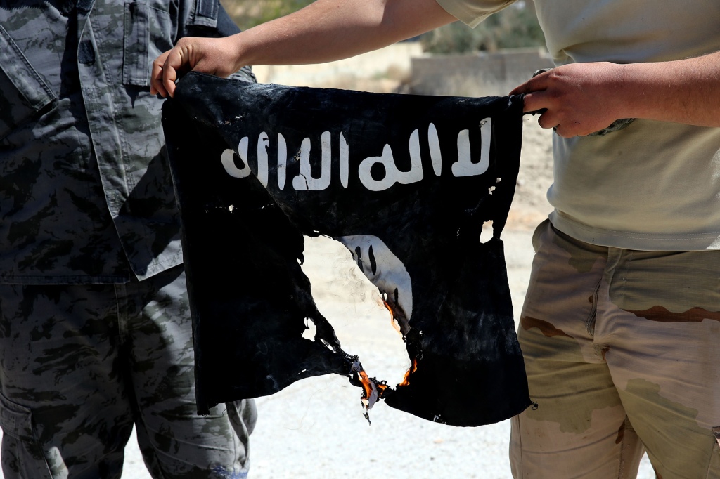 Syrian soldier sets fire on April 4, 2016 to an Islamic State (IS) group flag.