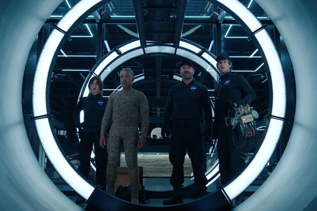 Paz Vega as Ava Mercer, Giancarlo Esposito as Leo Pap, Jai Courtney as Bob Goodwin, Peter Mark Kendall as Stan Loomis in "Kaleidoscope" standing in a round vault doorway. 