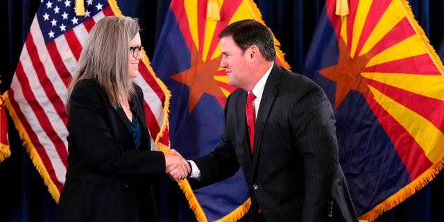 Katie Hobbs, the Democratic governor-elect and current secretary of state, left, shakes hands with Republican Gov. Doug Ducey after she signed the official certification for the Arizona general election canvass during a ceremony at the Arizona Capitol in Phoenix, Dec. 5, 2022.