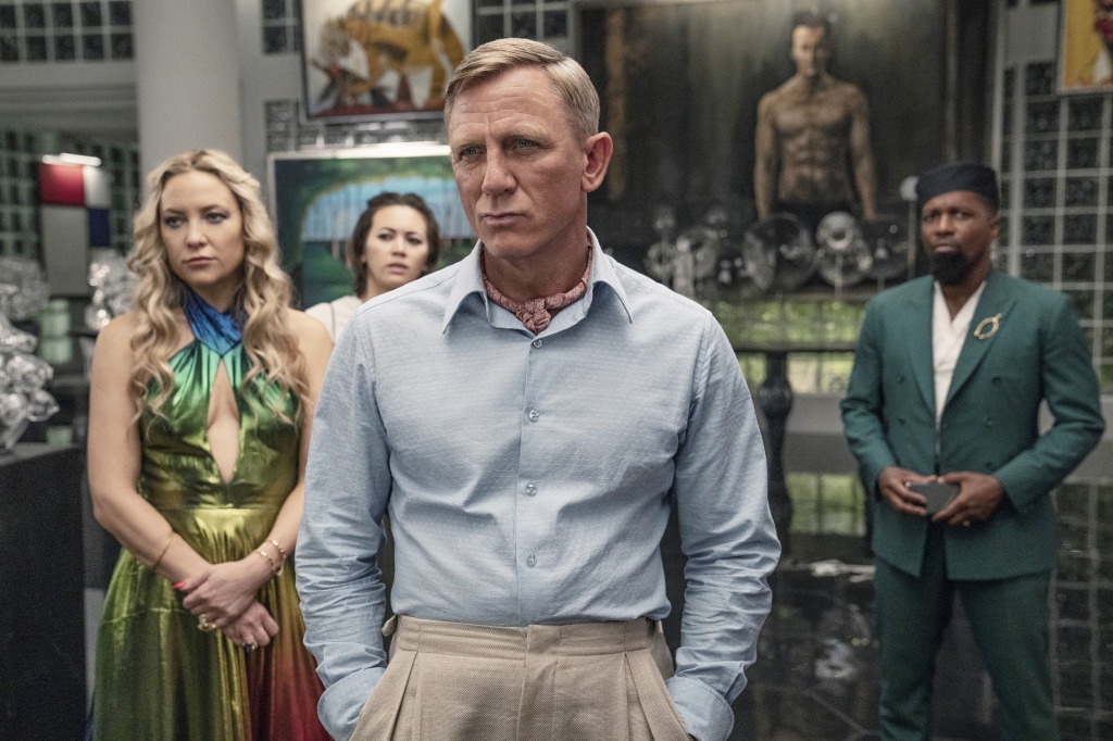  Kate Hudson, Jessica Henwick, Daniel Craig, and Leslie Odom Jr. in "Glass Onion" standing in a room. 