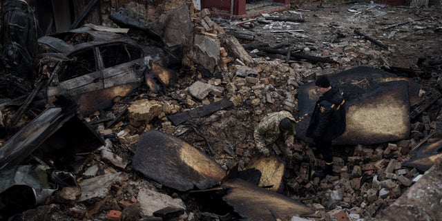 A Ukrainian firefighter and serviceman inspect a damaged house following a Russian drone attack in the village of Stari Bezradychi, Kyiv region, Ukraine, Monday, Dec. 19, 2022.