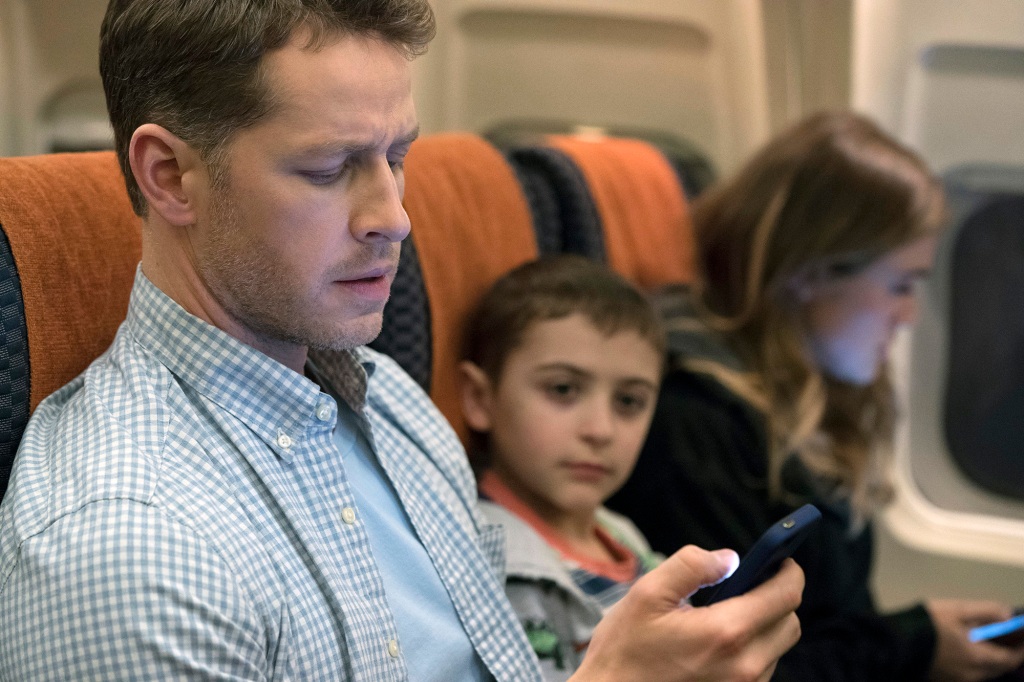 Photo of Ben, Cal and Michaela seated side by side on Flight 828. Ben is looking at his cellphone.