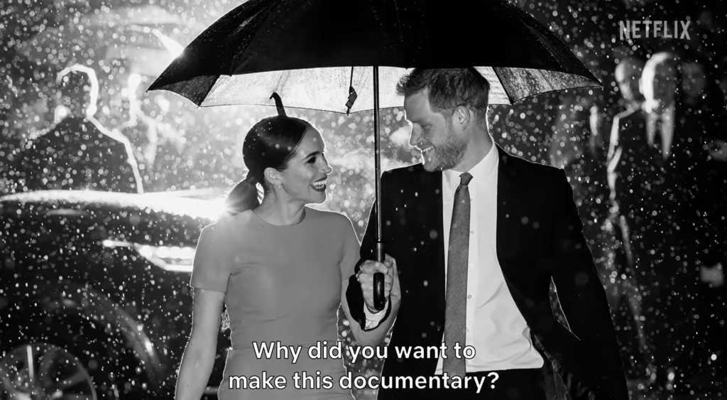 Meghan Markle and Prince Harry smile at one another under an umbrella.