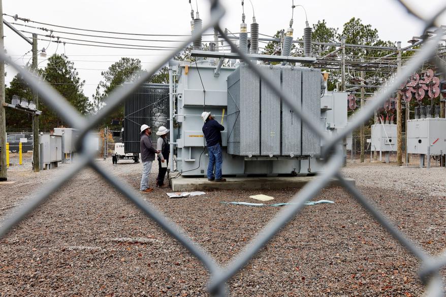 Duke Energy workers inspect one of the bullet holes that hit an electrical substation.