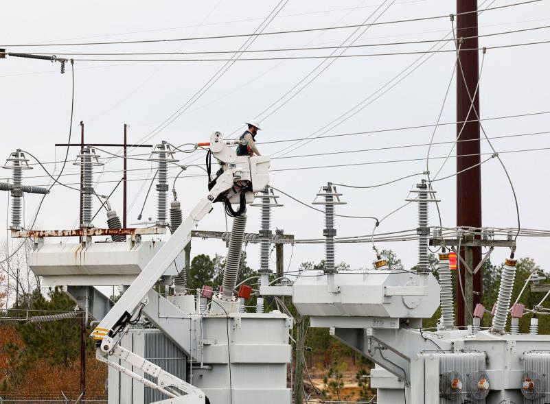 Duke Energy workers inspect one of the bullet holes that hit an electrical substation.