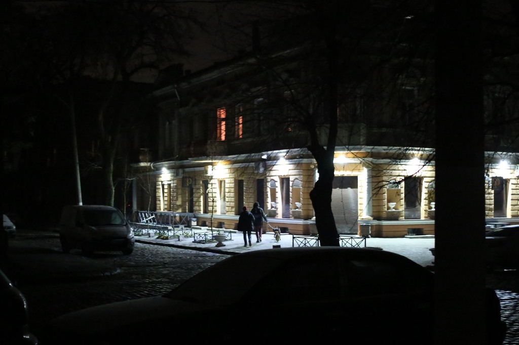 People walk their dog on Koblevska Street during a power outage on December 5, 2022 in Odesa.