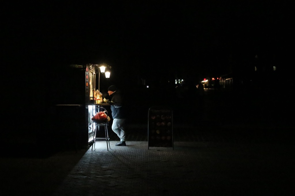 A visitor stands near a street cafe lit by cafe's lanterns during a power outage on December 5.